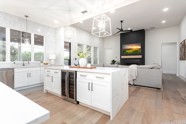 kitchen featuring open floor plan, hanging light fixtures, beverage cooler, and white cabinetry