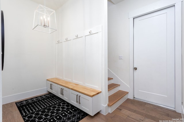 mudroom with a chandelier, wood finished floors, and baseboards