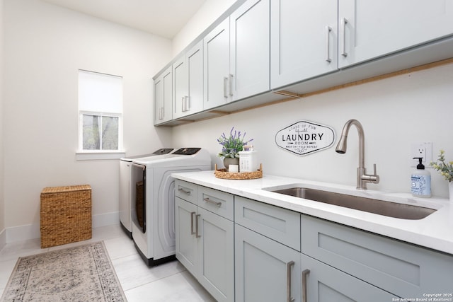 laundry room featuring washing machine and clothes dryer, cabinet space, light tile patterned flooring, a sink, and baseboards