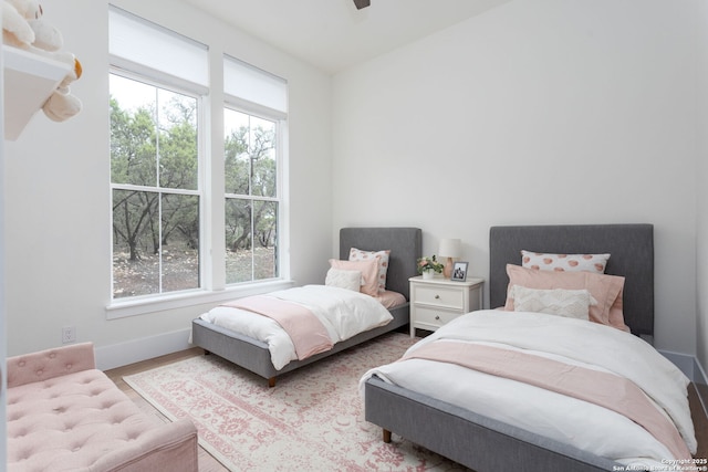 bedroom with light wood-style flooring, multiple windows, and baseboards