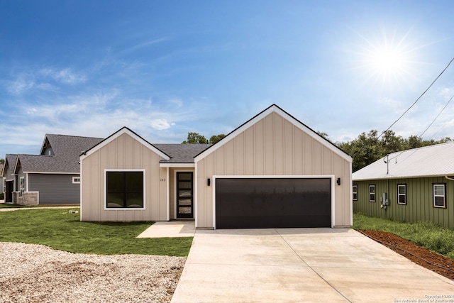 modern inspired farmhouse featuring a garage, a shingled roof, driveway, a front lawn, and board and batten siding