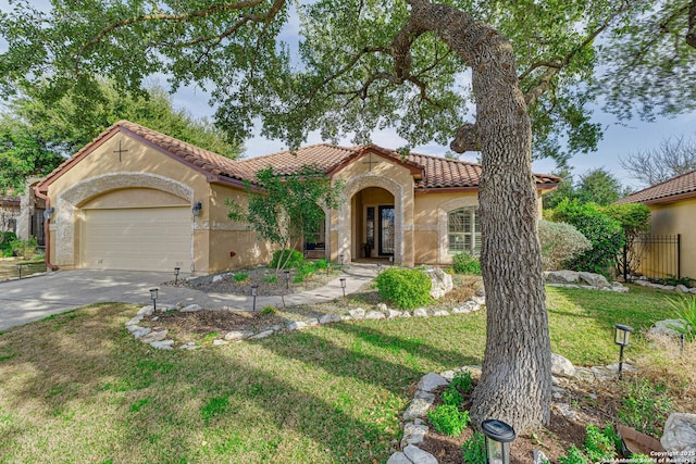 mediterranean / spanish-style home with stucco siding, concrete driveway, an attached garage, a front yard, and a tiled roof