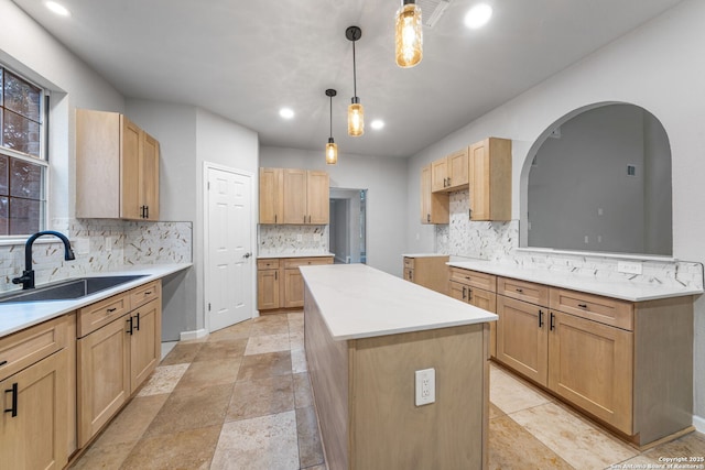 kitchen with a sink, a center island, hanging light fixtures, decorative backsplash, and light brown cabinetry