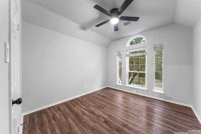 spare room with dark wood-style floors, lofted ceiling, visible vents, ceiling fan, and baseboards