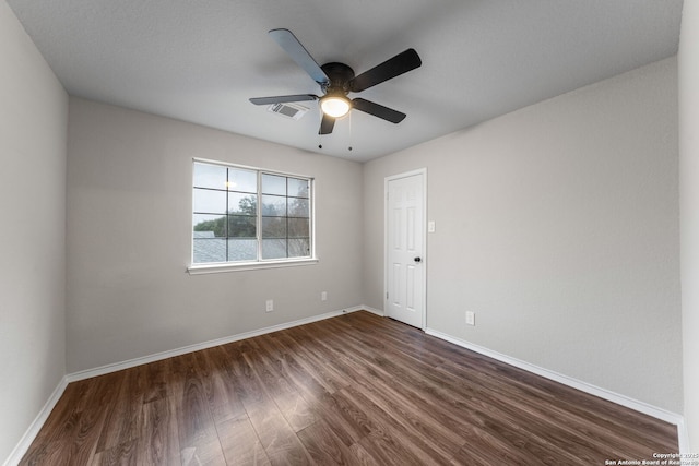 empty room featuring a ceiling fan, dark wood finished floors, visible vents, and baseboards