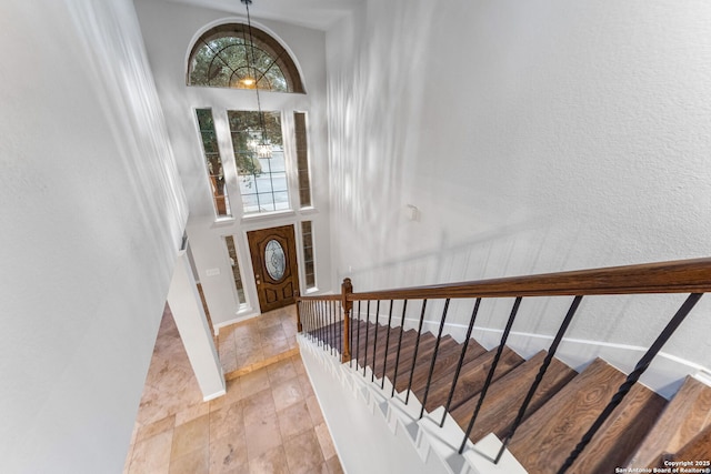 entryway featuring baseboards, a high ceiling, stairs, and a notable chandelier