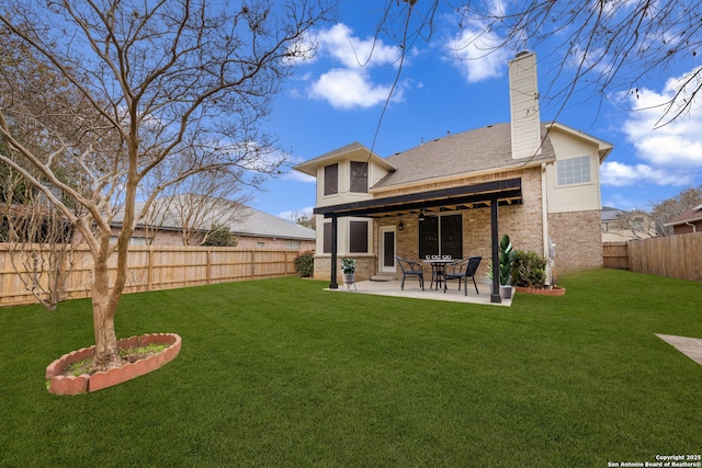 back of property with a patio, a fenced backyard, brick siding, a yard, and a chimney