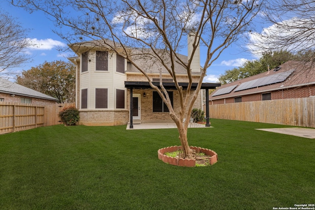 back of house with a yard, a fenced backyard, a patio, and brick siding