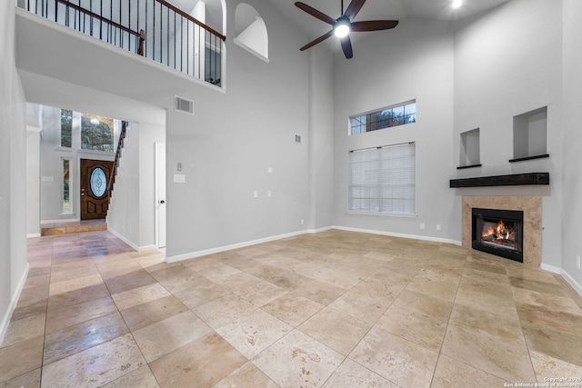 unfurnished living room with a ceiling fan, a tile fireplace, visible vents, and baseboards