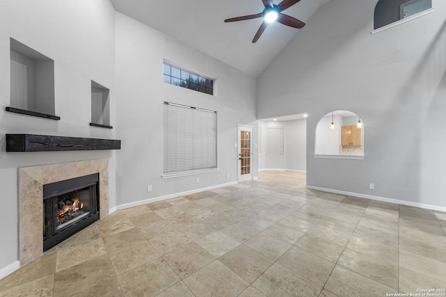 unfurnished living room featuring lofted ceiling, baseboards, ceiling fan, and a tiled fireplace