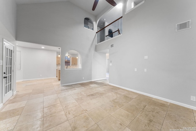 unfurnished living room featuring ceiling fan, visible vents, arched walkways, and baseboards