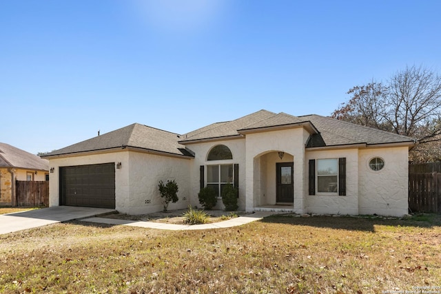 french country inspired facade featuring concrete driveway, a front yard, and fence