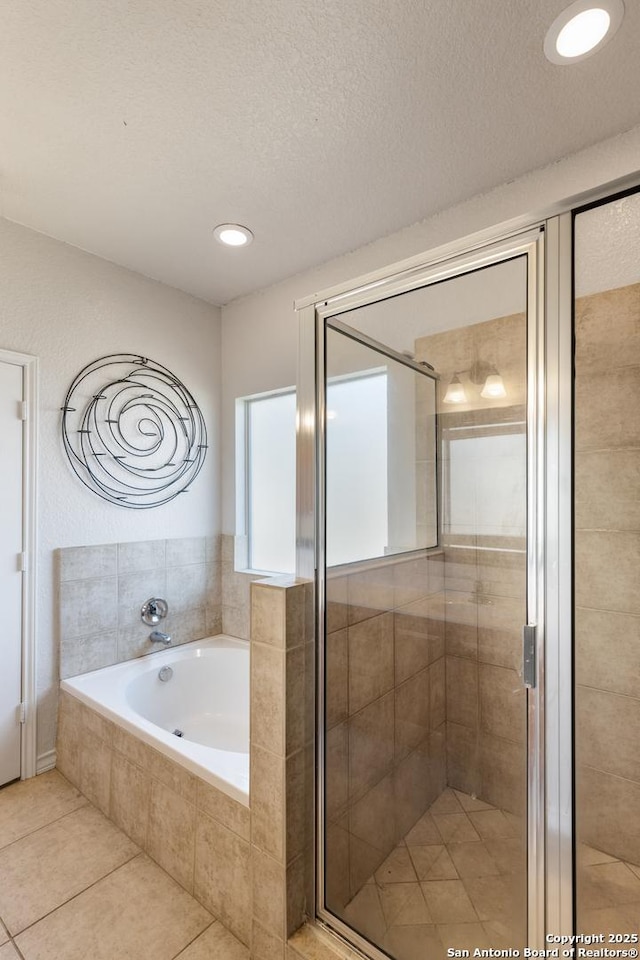 full bathroom featuring a stall shower, tile patterned flooring, a garden tub, and a textured ceiling