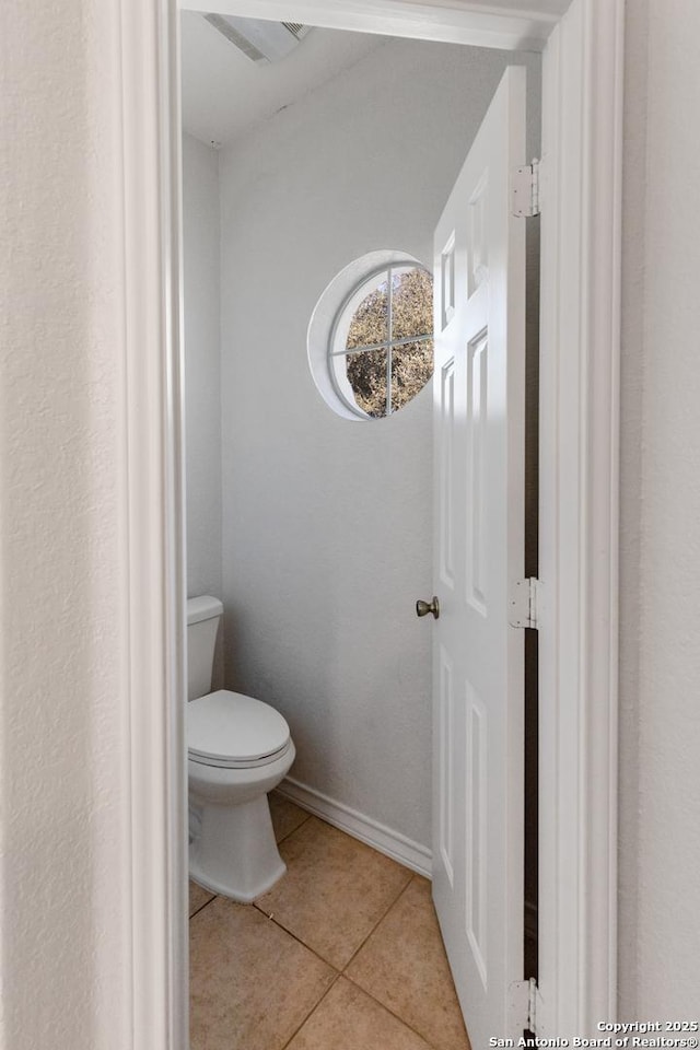 bathroom featuring toilet, baseboards, and tile patterned floors