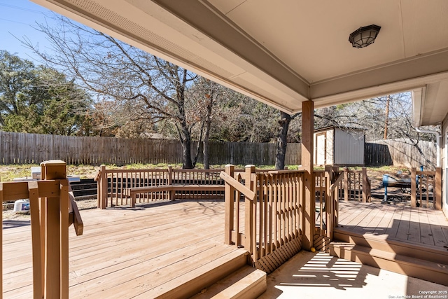 wooden deck with an outbuilding, a shed, and a fenced backyard