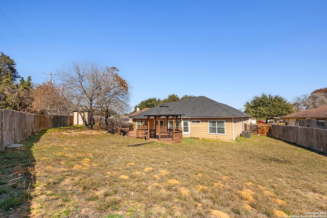 rear view of house with a fenced backyard, a deck, and a lawn