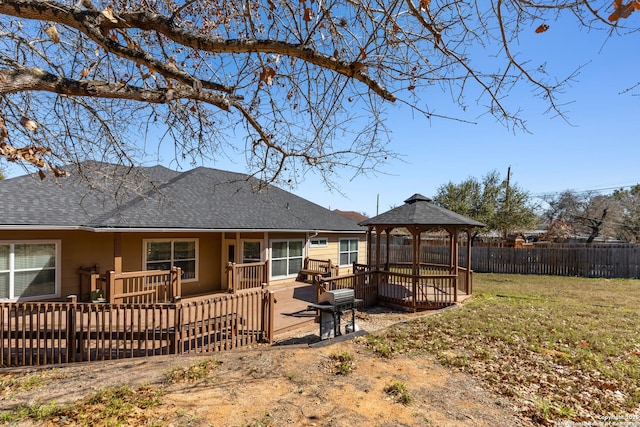 back of house with a lawn, roof with shingles, fence, a deck, and a gazebo