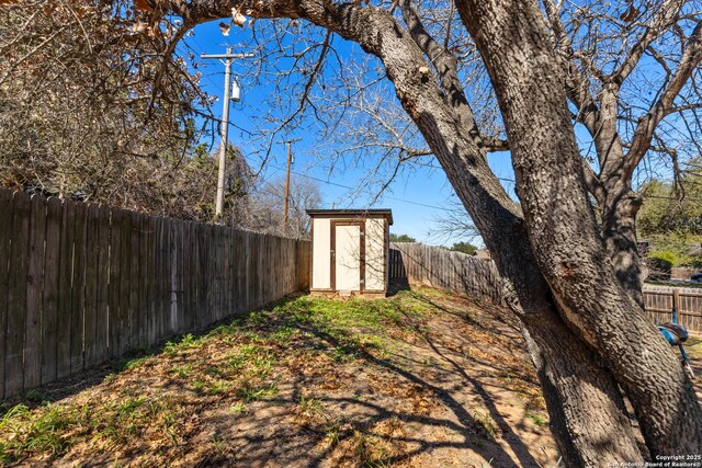 view of yard with an outbuilding, a fenced backyard, and a storage shed