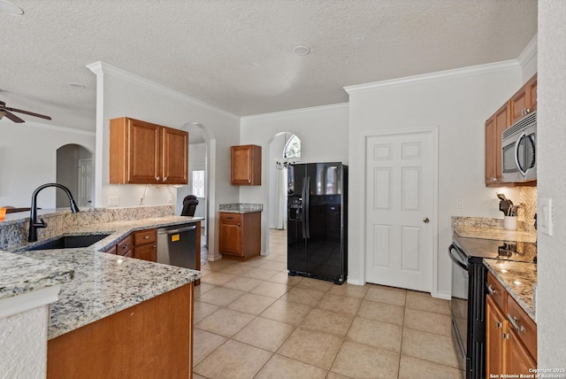 kitchen with arched walkways, brown cabinets, a sink, a peninsula, and black appliances