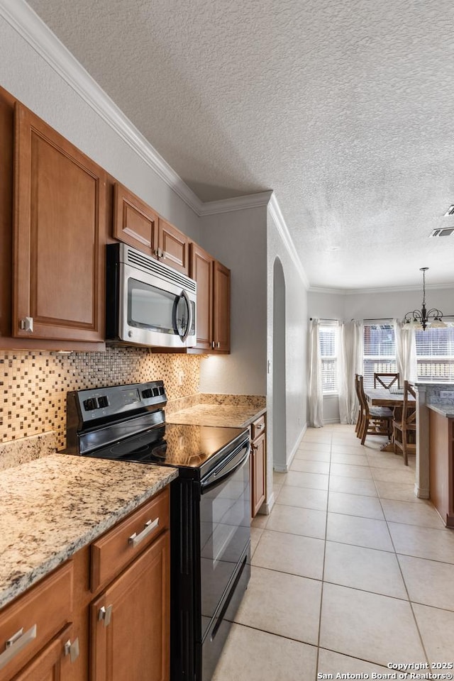 kitchen featuring arched walkways, tasteful backsplash, stainless steel microwave, hanging light fixtures, and black / electric stove