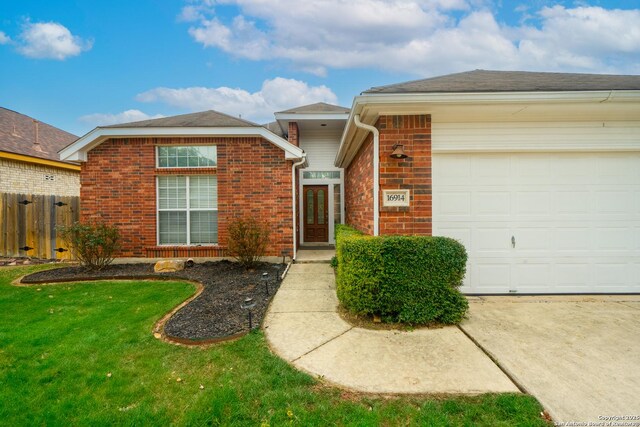 ranch-style home with brick siding, an attached garage, fence, and a front yard