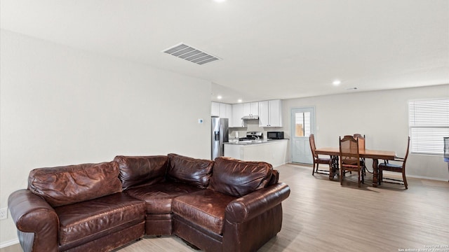 living area featuring baseboards, light wood-style flooring, visible vents, and recessed lighting