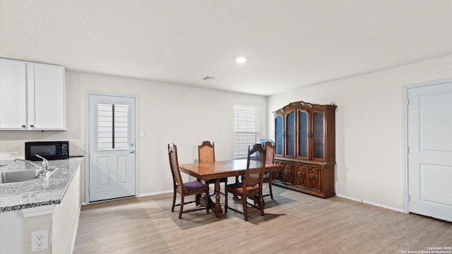 dining area featuring light wood-style floors, plenty of natural light, visible vents, and baseboards