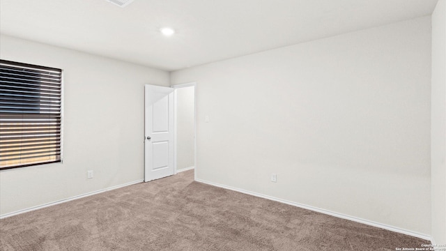 unfurnished room featuring carpet and baseboards