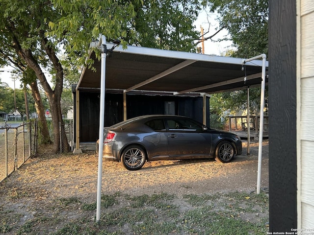 view of parking / parking lot with a carport and fence