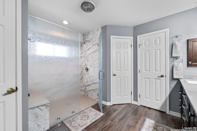 full bath with baseboards, a shower stall, vanity, and wood finished floors