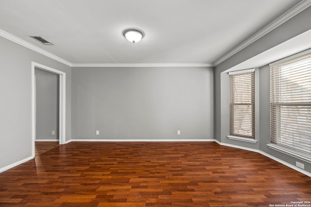 unfurnished room with dark wood-style floors, baseboards, visible vents, and crown molding