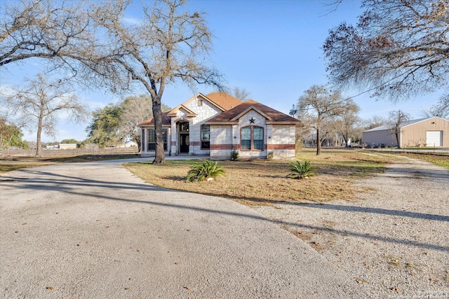 bungalow-style home featuring a garage, gravel driveway, and a front lawn