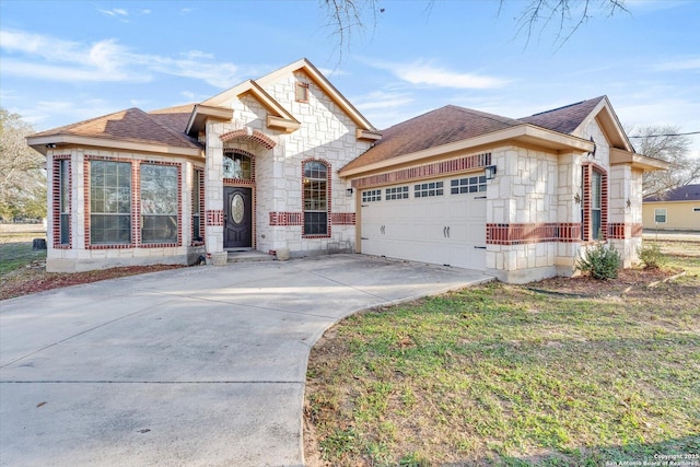 french country home with a shingled roof, stone siding, driveway, and an attached garage