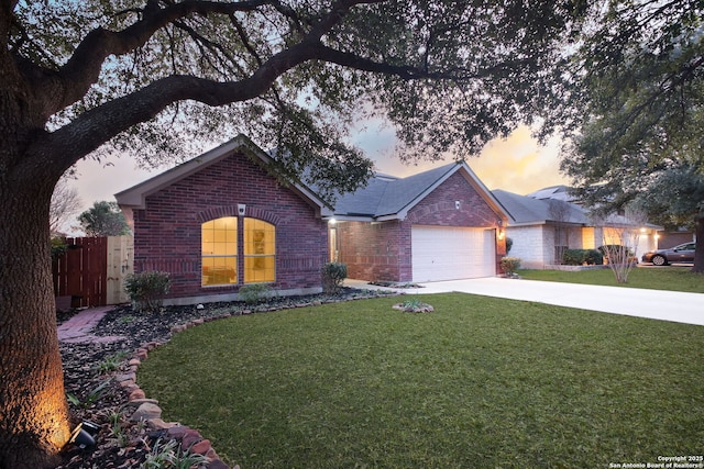 single story home with brick siding, concrete driveway, fence, a garage, and a front lawn