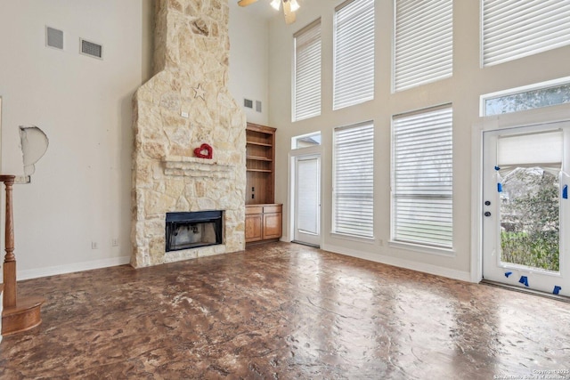 unfurnished living room featuring a stone fireplace, visible vents, and baseboards