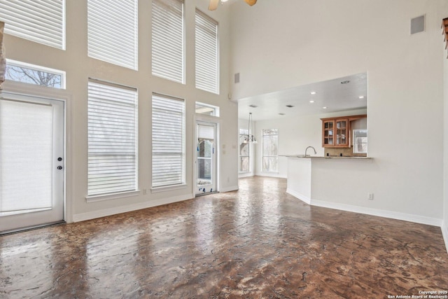 unfurnished living room featuring recessed lighting, a high ceiling, a sink, visible vents, and baseboards