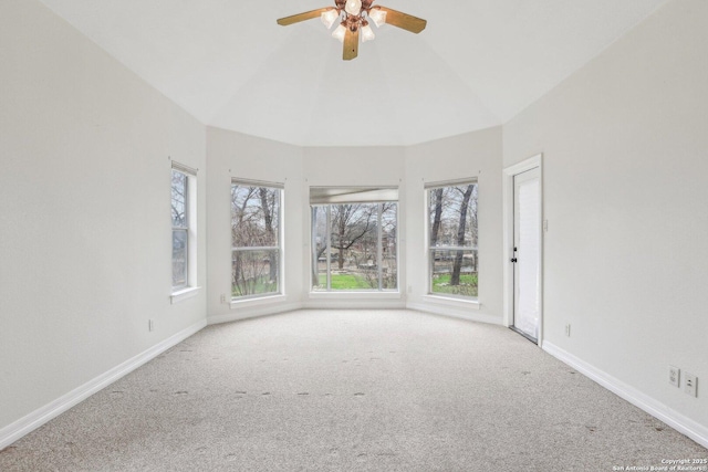 empty room featuring light carpet, ceiling fan, vaulted ceiling, and baseboards