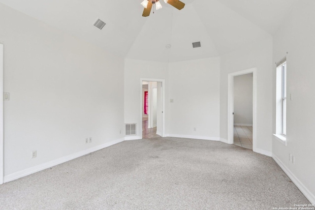 spare room featuring a healthy amount of sunlight, high vaulted ceiling, carpet, and visible vents