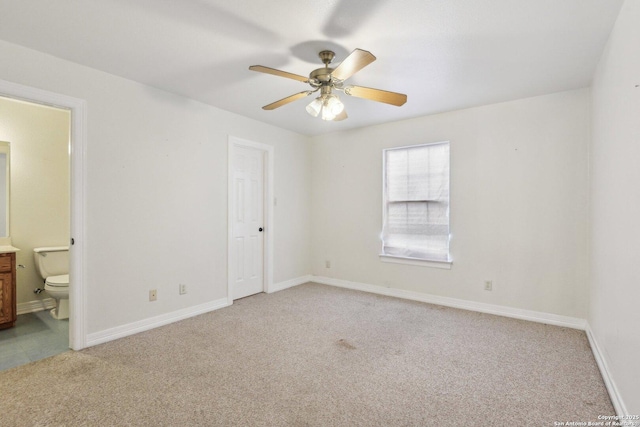 unfurnished bedroom with light carpet, ceiling fan, ensuite bath, and baseboards