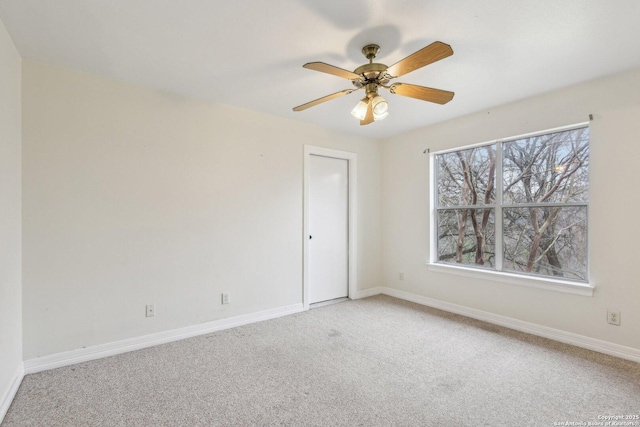 carpeted spare room with ceiling fan and baseboards