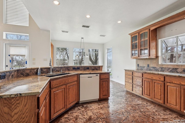 kitchen with visible vents, glass insert cabinets, white dishwasher, pendant lighting, and a sink