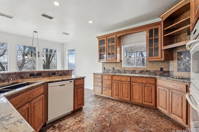 kitchen featuring decorative light fixtures, brown cabinets, visible vents, glass insert cabinets, and white appliances