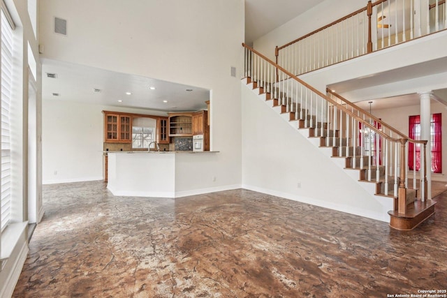 unfurnished living room with recessed lighting, visible vents, stairway, a towering ceiling, and baseboards