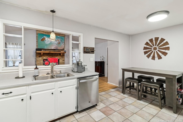 kitchen with light countertops, dishwasher, a sink, and white cabinetry