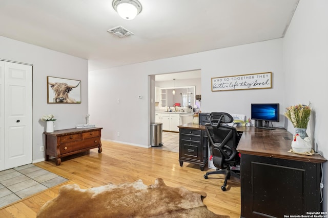 office area featuring light wood finished floors, baseboards, and visible vents