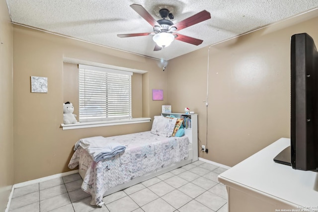 bedroom with light tile patterned floors, a ceiling fan, baseboards, and a textured ceiling