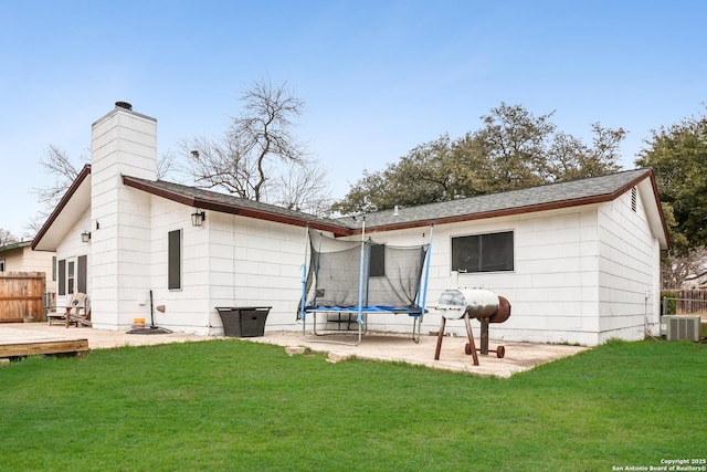 rear view of property with central AC unit, a yard, a trampoline, fence, and a wooden deck