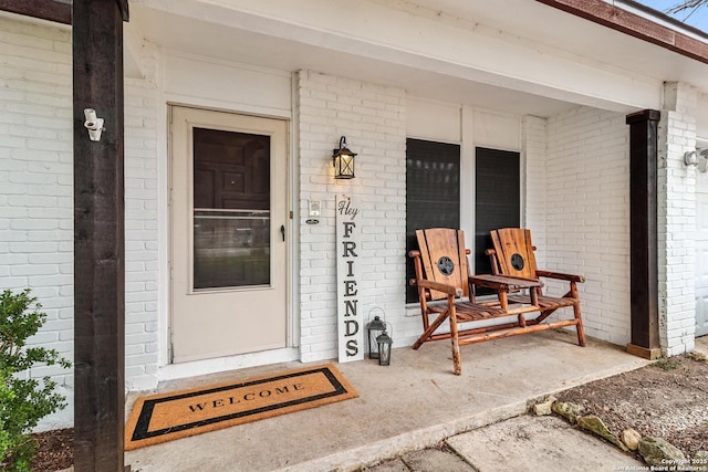 property entrance featuring a porch and brick siding