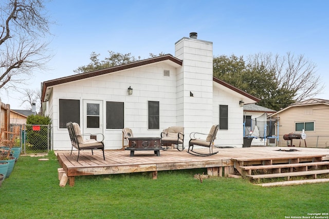 rear view of house with a chimney, fence, a lawn, and a wooden deck