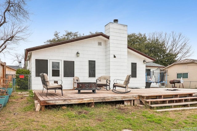 rear view of property with fence, a chimney, and a wooden deck